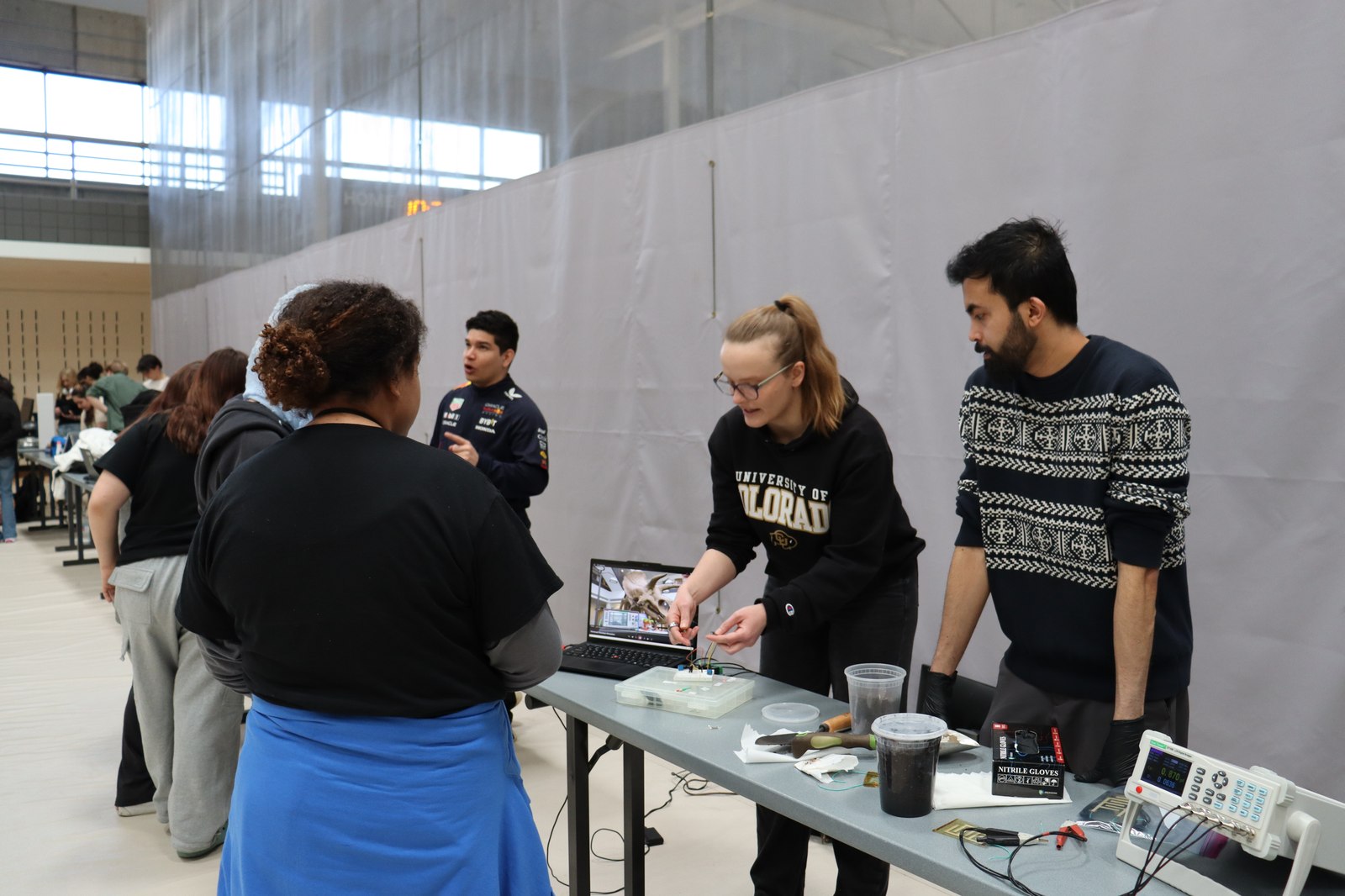 BEEM Lab members demonstrating a benchtop electronics setup to K-12 students and teachers at a science fair.